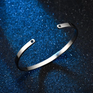 Detailed close-up of a silver C-shaped stainless steel cuff bracelet on a blue starry background
