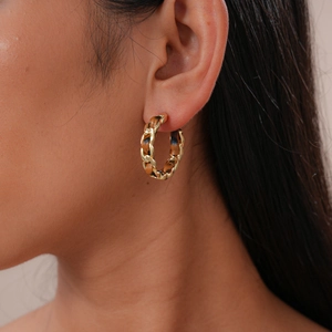 Détail de la boucle d'oreille en C avec chaîne dorée et cuir tressé marron sur modèle