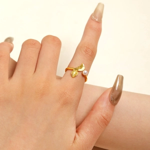Detail of adjustable golden mermaid tail ring with a small white pearl on finger