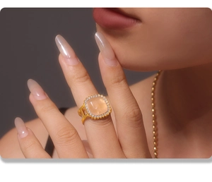 Close-up of gold plated ring with square orange natural stone and zircon settings