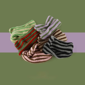 Macro shot of assorted colorful striped knit beanies in various thick woven patterns