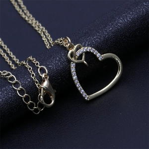 Close-up of gold heart pendant with cubic zirconia inlay and lobster clasp detail