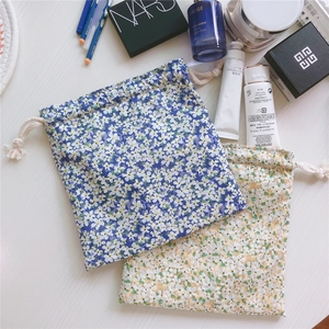 Detail view of floral cotton drawstring pouches with makeup items on a white desk