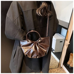 Fashionable dark brown ruched cloud tote bag with round handle shown on a model