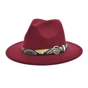 Detail of burgundy fedora hat featuring a snake print belt and gold horseshoe buckle