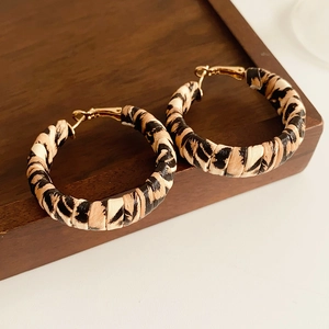 Detailed view of vintage leopard print hoop earrings on a dark wooden tray