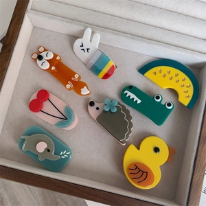 Detailed top view of colorful acetate animal and fruit hair clips in a wooden display box