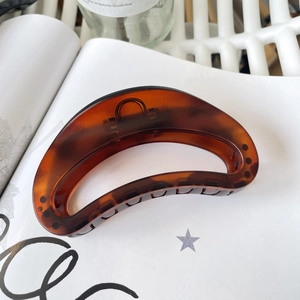 Macro detail of large amber tortoiseshell resin hair claw clip on minimalist magazine