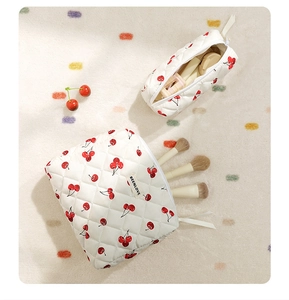 Detail of white quilted makeup bags featuring red cherry patterns in two sizes