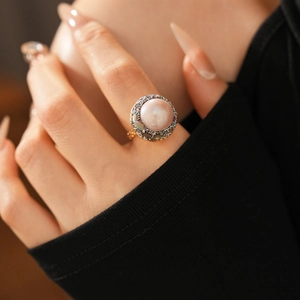 Detailed view of a vintage gold ring with large pearl and colorful zircon accents