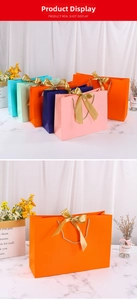 Detail of colorful gift bags with golden satin bows and woven handles on marble