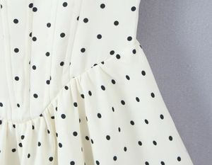Detailed close-up of the pleated waist design on a white polka dot French style dress