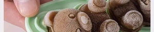 Macro detail of flexible green silicone bear mold with frozen brown ice cubes