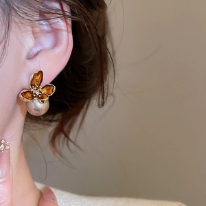 Detail of amber flower earrings with a large white pearl and sparkling center zircon