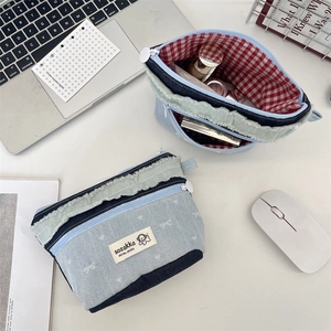 Detailaufnahme der Jeans-Patchwork-Kosmetiktasche mit rot-weiß kariertem Innenfutter