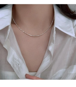 Detailed view of a silver minimalist clavicle necklace worn on the model's neck