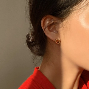 Gros plan sur les boucles d'oreilles cœur dorées portées pour un aspect raffiné et chic