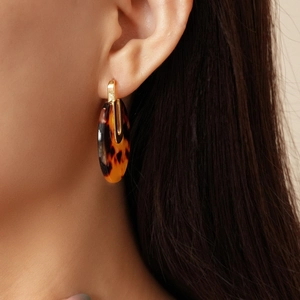 Detailed close-up of circular tortoise shell earrings with 18K gold-plated accents