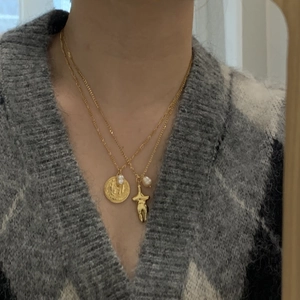 Double-layered gold necklace with Virgin Mary coin pendant, pearls, and human figure charm