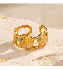 Vue macro d'une bague coeur dorée avec points en émail coloré sur socle pierre
