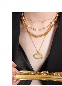 Close-up of layered titanium steel gold necklaces with pearls and oval pendant on model