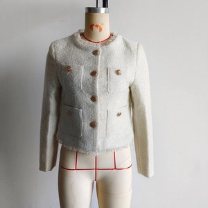 Detail der weißen Tweed-Jacke mit Fransenrand und dekorativen goldenen Prägeknöpfen