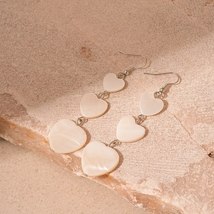 Detail of elegant triple heart drop earrings with shimmering mother of pearl texture
