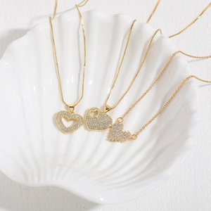 Close-up of gold heart pendants with cubic zirconia on a white shell display