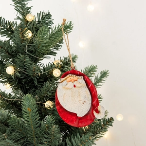 Vintage painted metal Santa Claus hanging ornament on Christmas tree with warm lights