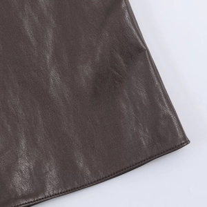 Détail de la jupe en similicuir marron foncé avec texture fine et coutures soignées