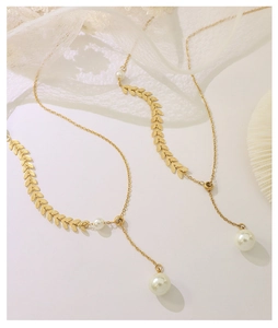 Detail of 18k gold plated necklace with wheat leaf chain and elegant white pearl drop