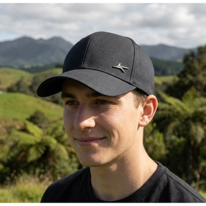 Detail of black baseball cap with silver metal bird logo worn outdoors by man