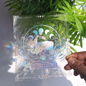 Handheld holographic rainbow suncatcher sticker featuring whale and moon phase designs