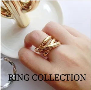 Detailansicht eines mehrlagigen goldenen Kreuzrings, am Finger getragen, edles Design