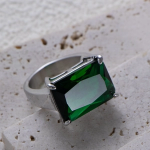 Macro detail of a large emerald cut green gemstone on a polished silver ring band