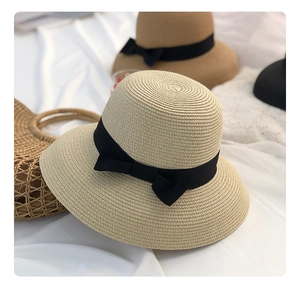 Detailed close-up of straw sun hat weaving with elegant black ribbon and bow