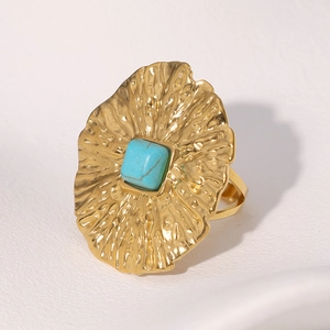 Vue détaillée d'une bague dorée vintage sertie d'une pierre bleue carrée et métal martelé