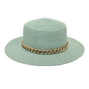 Détail d'un chapeau de paille vert menthe avec une décoration de chaîne en acrylique dorée