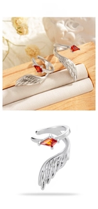 Detail of silver wing ear cuffs featuring a red rhombic zircon and feather patterns