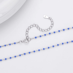 Close-up of S925 sterling silver stamp on minimalist chain necklace with blue beads