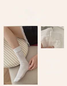 Close-up of white ribbed crew socks with delicate lace trim and sweet fabric label