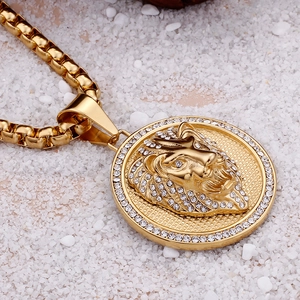 Gold-plated lion head pendant necklace with rhinestones on white stones background