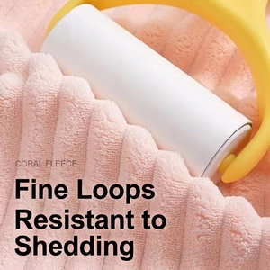 Manual lint roller with yellow handle cleaning hair from soft coral fleece towel fabric