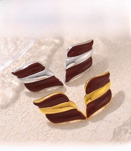 Macro shot of wing-shaped earrings with red enamel and PVD gold plating detail