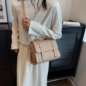 Detail of beige leather crossbody bag with buckle decor and adjustable shoulder strap