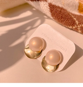 Close-up of elegant gold twisted circle earrings with champagne pearls on a jewelry card