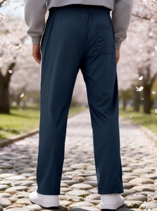 Back view of navy blue men's loose sports joggers against a blooming cherry tree background