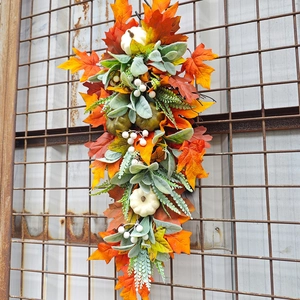 Close-up of autumn swag with white pumpkins, maple leaves, and berries on a metal grid