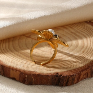 Detailed macro view of a gold flower ring with a white pearl and blue gemstone center