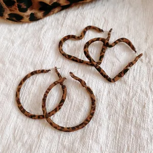 Boucles d'oreilles créoles et coeurs à motif léopard sur fond de texture blanche